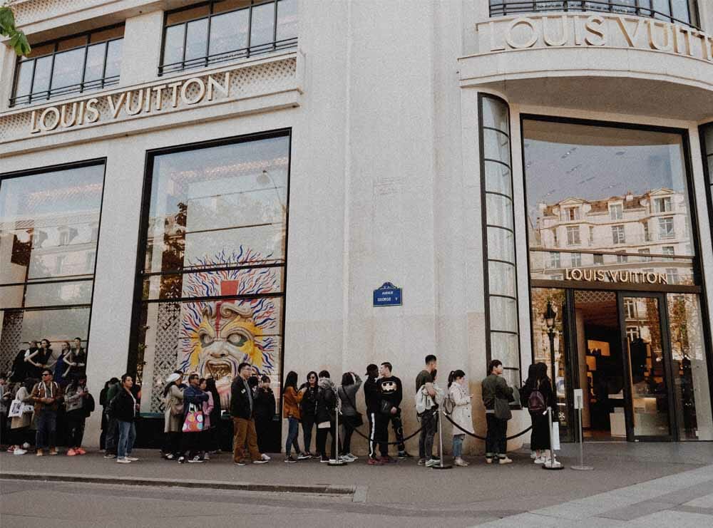 people stood outside of a Louis Vuitton store