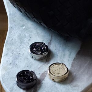 Trio of LUXAWL table bag hooks in black, silver and gold on a white marble table.