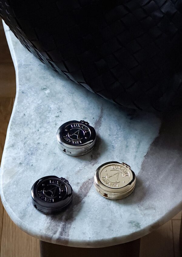 Trio of LUXAWL table bag hooks in black, silver and gold on a white marble table.